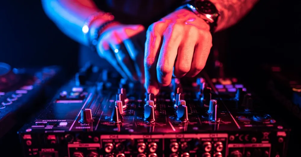 DJ-Hände steuern einen Musiktisch in einem Nachtclub